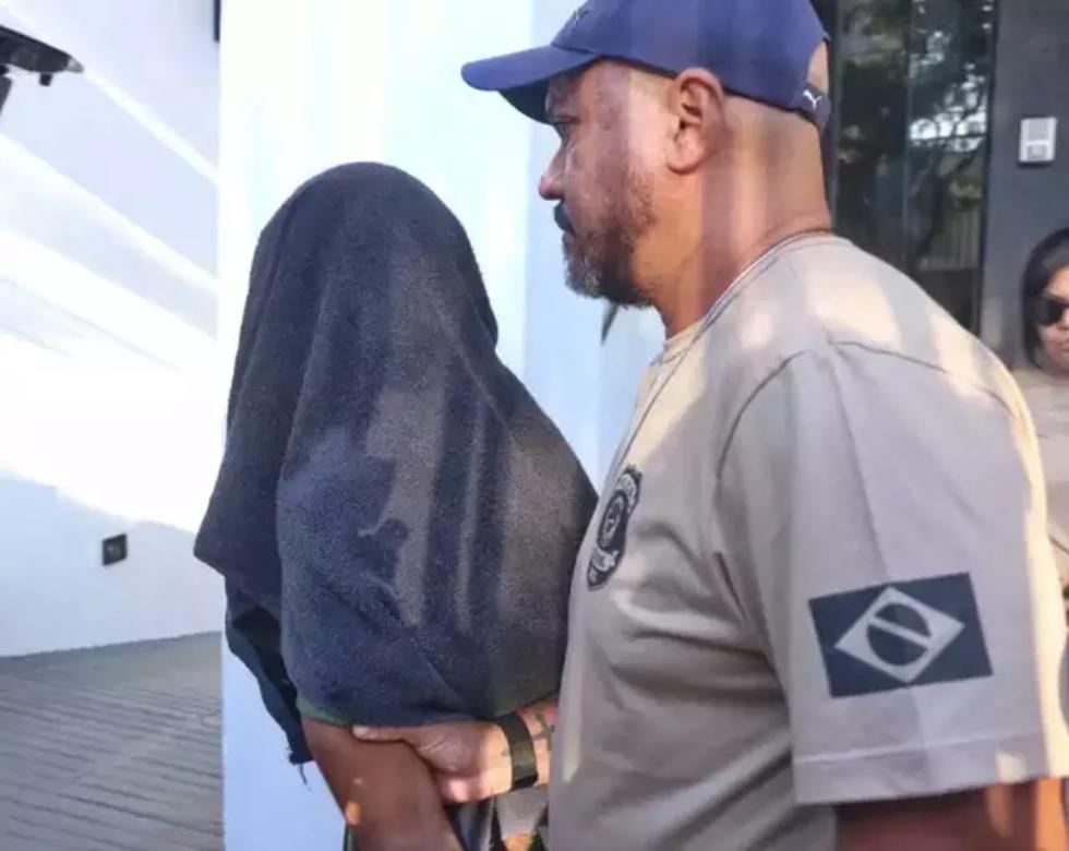 Maykon chegando à Depca com a cabeça coberta por uma toalha.